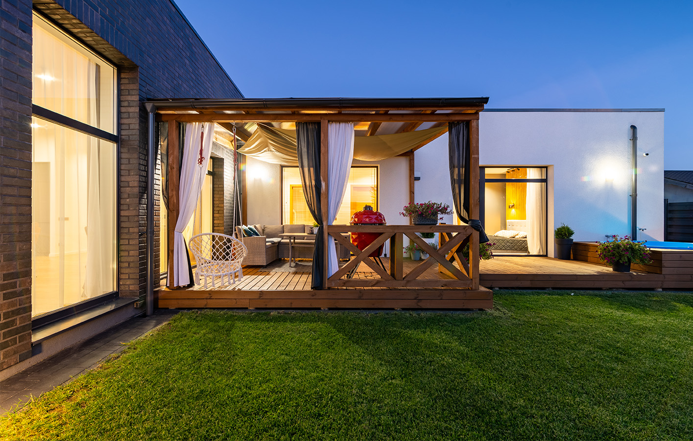 Überdachte Terrasse mit gemütlichen Möbeln und stimmungsvoller Beleuchtung.